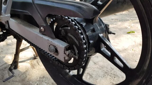 Motorcycle chain and rear wheel rotating during mechanical operation, showing sprocket movement and drivetrain motion.