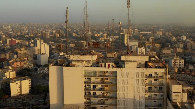 Aerial close up of skyscraper's rooftop overlooking large city urban sprawl in Africa