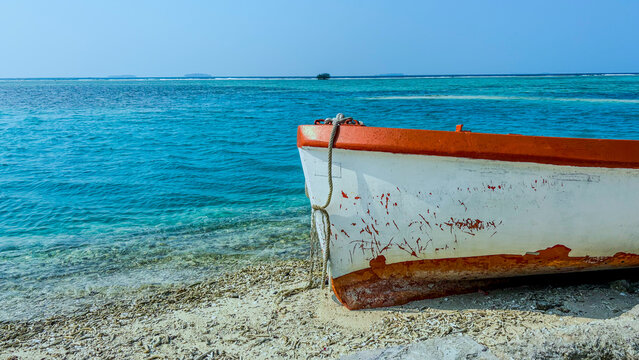 Front view of weathered wooden boat bow on tropical beach shore