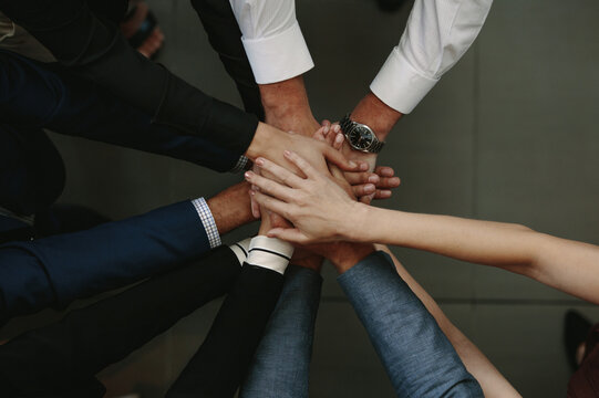 Diverse business team stacking hands together for unity and corporate teamwork success