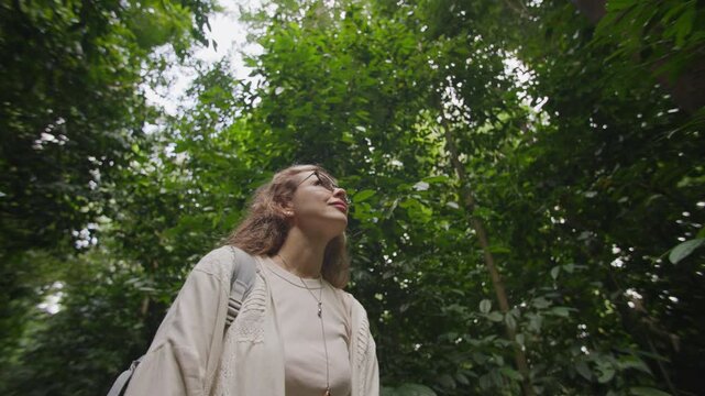 Woman walking through a tropical rainforest surrounded by lush exotic nature enjoying peaceful landscapes and an inspiring outdoor lifestyle adventure
