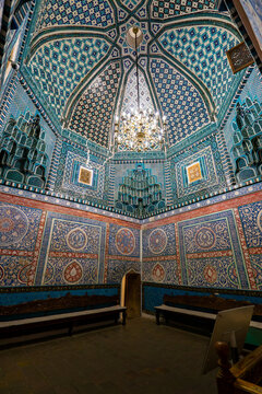 Ceiling decorated with blue mosaic in a room. Chandelier hanging from tiled ceiling. Indoor Islamic architecture. Central Asian interior.