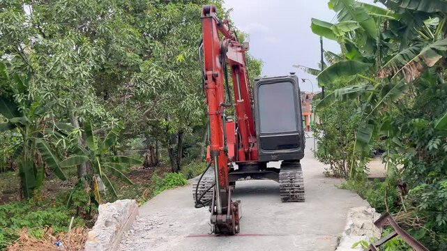 Orange hydraulic crawler excavator parked on rural road construction site