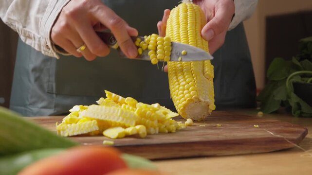 Fresh corn being cut from the cob with a knife