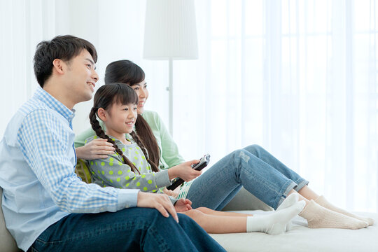 ソファーに座ってテレビを見る家族