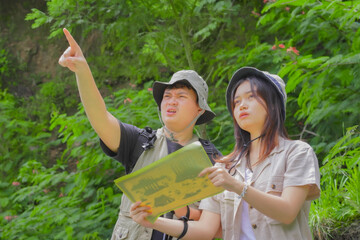 Fototapeta premium Young Asian couple is examining a hiking trail map they brought with them.
