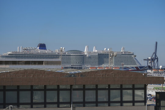 Massive gigantic modern cruiseship cruise ship liner Iona or Arvia in Cadiz, Spain during summer Mediterranean cruising with harbor and container port infrastructure
