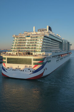 Massive gigantic modern cruiseship cruise ship liner Iona or Arvia in Cadiz, Spain during summer Mediterranean cruising with harbor and container port infrastructure