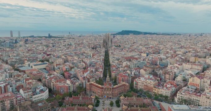 Cinematic aerial of Barcelona city skyline. Drone fly over Eixample residential famous urban grid and Sagrada Familia cathedral with morning sunrise cityscape. Catalonia, Spain. Travel Destination.