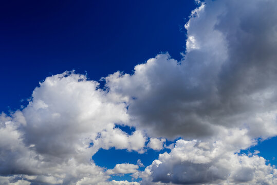 dense cumulus clouds with dark shadows filling a blue summer sky