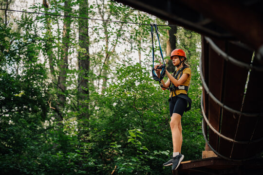 Young woman preparing for ziplining adventure in rope park