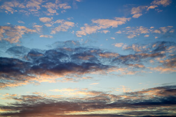 Fototapeta premium dramatic sunset with dense dark cloud formations illuminated by soft orange peach glow