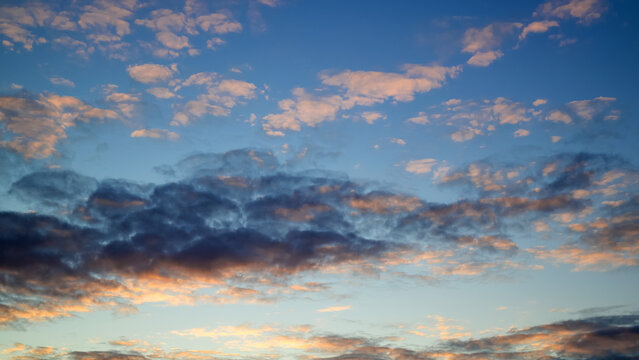 dramatic sunset sky filled with dark contrast clouds and gold illuminated ripple cloudlets