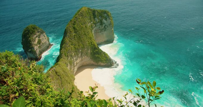 Turquoise ocean water crashes against white sand beach at Kelingking Cliffs Bali Nusa Penida