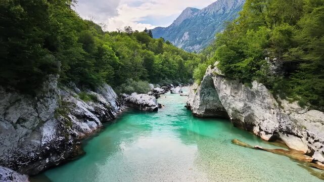 Aerial drone view of the emerald river between white rocks with the mountains rising behind, Soca Valley, Slovenia