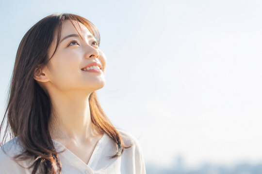 青空を見上げて微笑む日本人女性 Generative AI