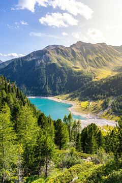 Lake Neves sits at the end of the Molini Valley in South Tyrol, Italy. The sun shines on the clear water and mountains, showcasing nature's beauty in this remote area.