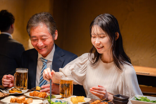 若い女性と二人で食事をする中年のビジネスマン