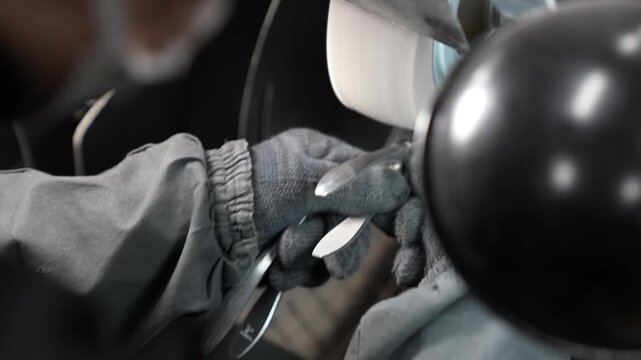 Worker buffing a nail clipper tool on a rotating polishing wheel machine
