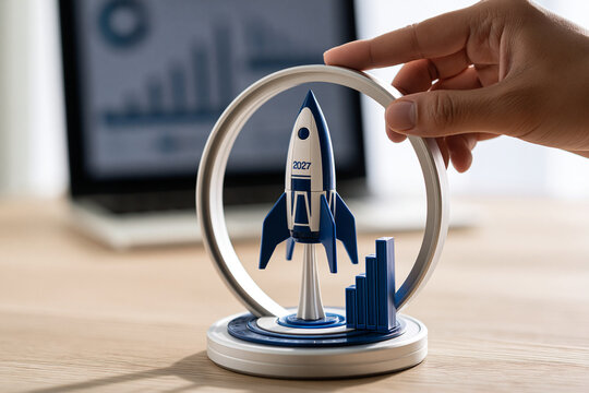 A hand adjusts a model rocket with business growth charts in a bright office.