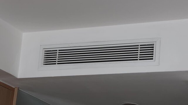 Modern white ceiling vent installed in clean indoor space. Simple design blends seamlessly into minimalist architecture. No people present. Focus remains on functional ventilation feature