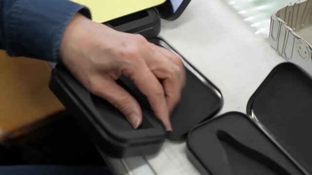 Hand placing finished nail clippers into black foam lined packaging trays