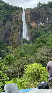Man taking photos of majestic Diyaluma waterfall with camera in Sri Lanka.