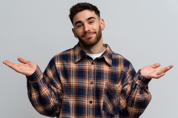 Naklejka premium Smiling young man shrugging with palms up in a plaid shirt for social content and relaxed lifestyle banner imagery