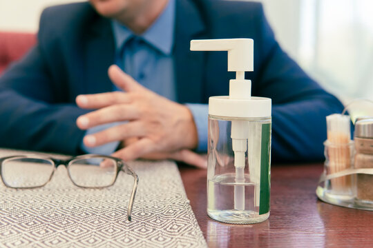 Hand disinfection with alcohol gel. bottle of disinfectant in close-up on a table in a cafe against the background of a businessman's hands.