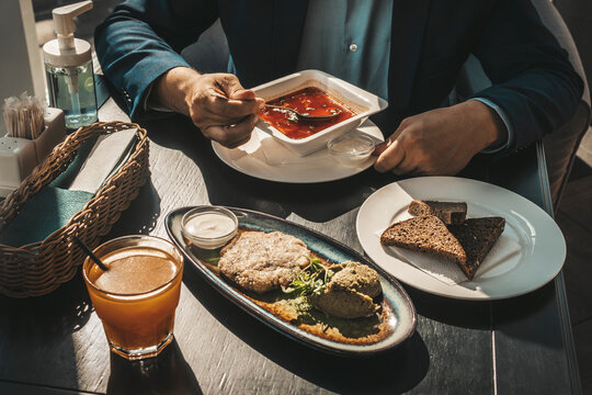 a man in a jacket is having lunch at a black table. Lunch break. Young handsome businessman eating lunch in a cafe