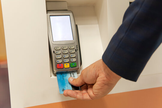 Payment with credit card - businessman holding pos terminal. Male hand dials pin code on pin pad of card machine or pos terminal with inserted blank credit card.