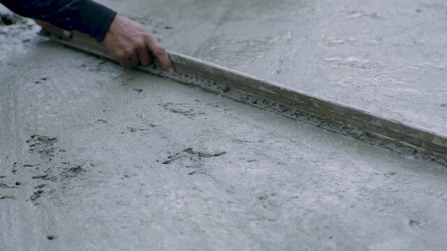 Hand Guiding Screed Over Wet Concrete