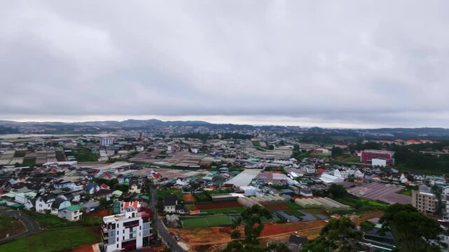 Aerial panning shot of urban landscape with sprawling city under cloudy sky