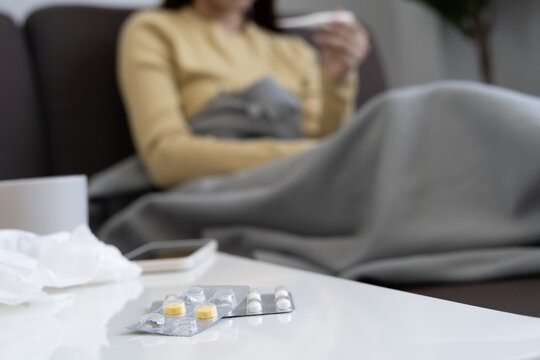 Young Asian woman having high fever while checking body temperature, female sneezing and runny nose with seasonal influenza, taking medicine, virus, coronavirus, illness, respiratory, allergic