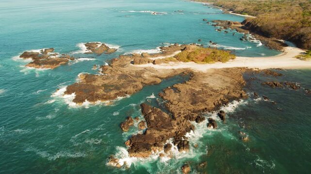 Scenic aerial view of rocky island coastline with waves breaking along the shore