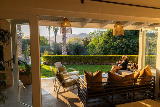 elderly man in beautiful outdoor patio overlooking vast garden and mountains at sunset