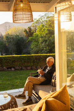 elderly man in beautiful outdoor patio overlooking vast garden and mountains at sunset
