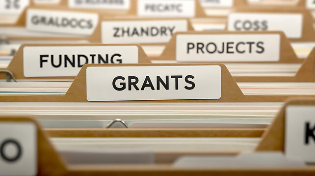 A close up view of brown paper filing folders with tabs labeled with text including funding, grants, and projects labels