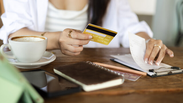 close-up shot, hand of young female holding credit card and checking financial bills, receipt before paying credit card debt