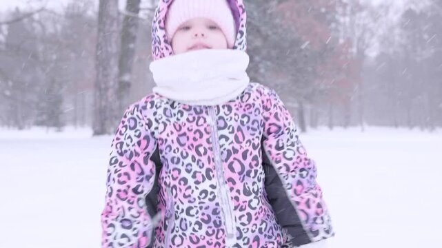 Toddler winter snow. Child cleaning snowy mittens in winter park.