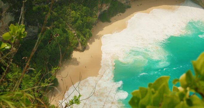 Powerful ocean waves crash on pristine sand of Kelingking Beach Nusa Penida