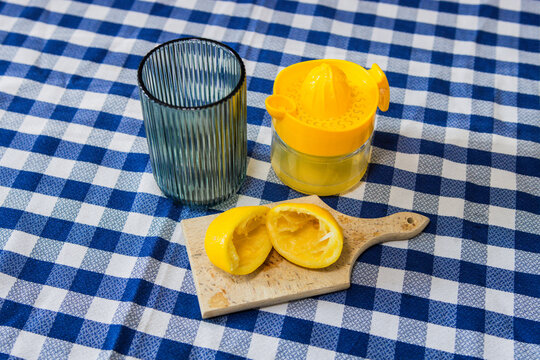 A squeezed lemon, a fruit strainer, and a glass on a kitchen table. Making homemade lemonade. Healthy lemon drink.