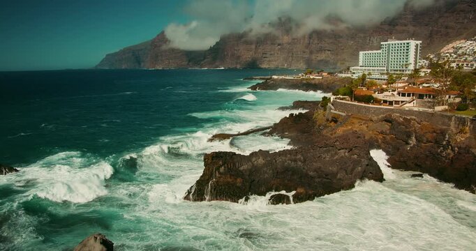 Stormy ocean crash on rocky volcanic shore in Tenerife Canary Islands. Sea waves foam splashing on igneous rocks in slow-motion.