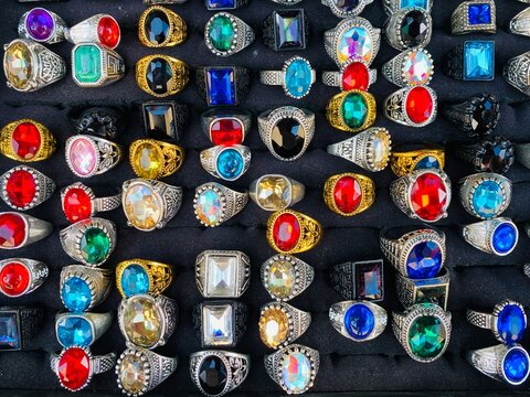 Colorful Gemstone Rings Collection Displayed on Black Fabric at Market