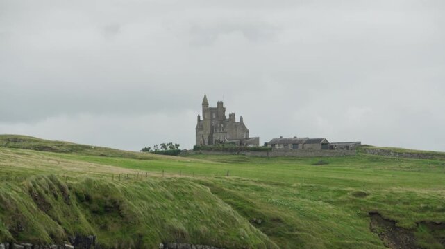 Telephoto view of Classiebawn Castle and nearby estate buildings rising above green coastal fields at Mullaghmore Head in County Sligo, Ireland.