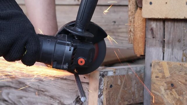 Worker cuts metal reinforcement with an angle grinder, repair work, hand tools, construction, cordless tool, cordless grinder. Cutting metal with a grinder with sparks. Professional power tool
