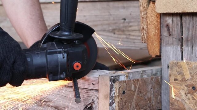 Worker cuts metal reinforcement with an angle grinder, repair work, hand tools, construction, cordless tool, cordless grinder. Cutting metal with a grinder with sparks. Professional power tool