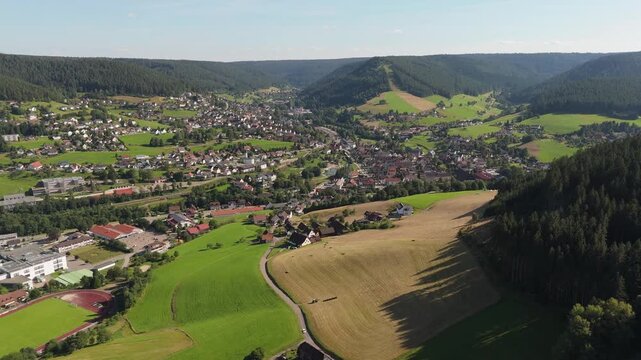 Aerial drone push in shot of Baiersbronn in the Black Forest, Germany, amidst lush valleys and residential areas.