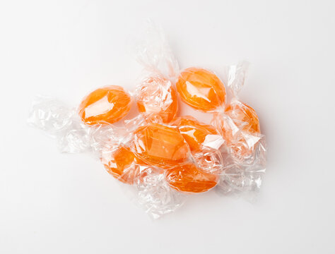 Orange hard candies isolated. Scattered lollipop pile, wrappers fruit confectionery group, round sweets
