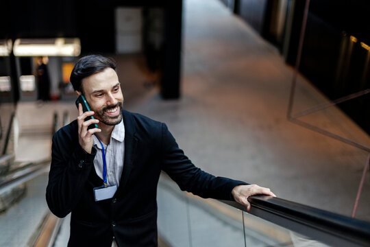 Smiling professional man talking on smartphone on escalator